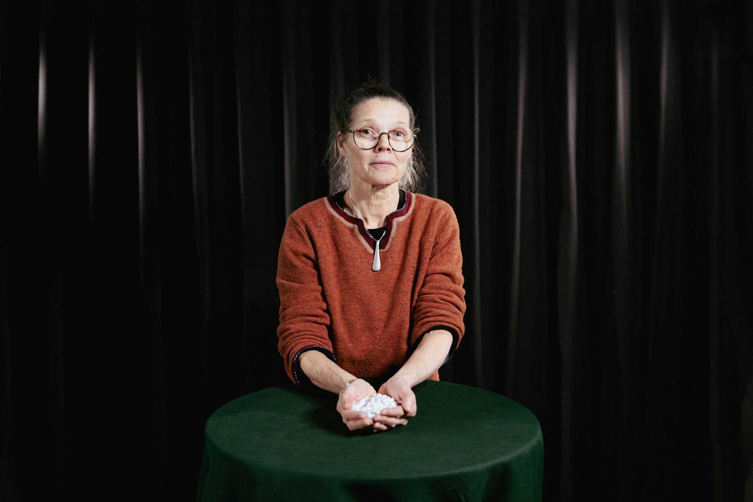 Kvinna vid ett bord håller medicin i händerna