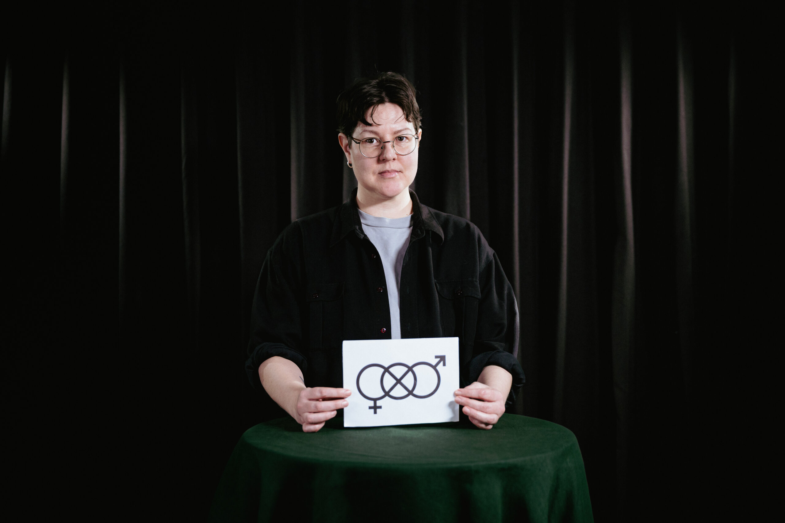 person med skylt med genderneutral symbol i handen